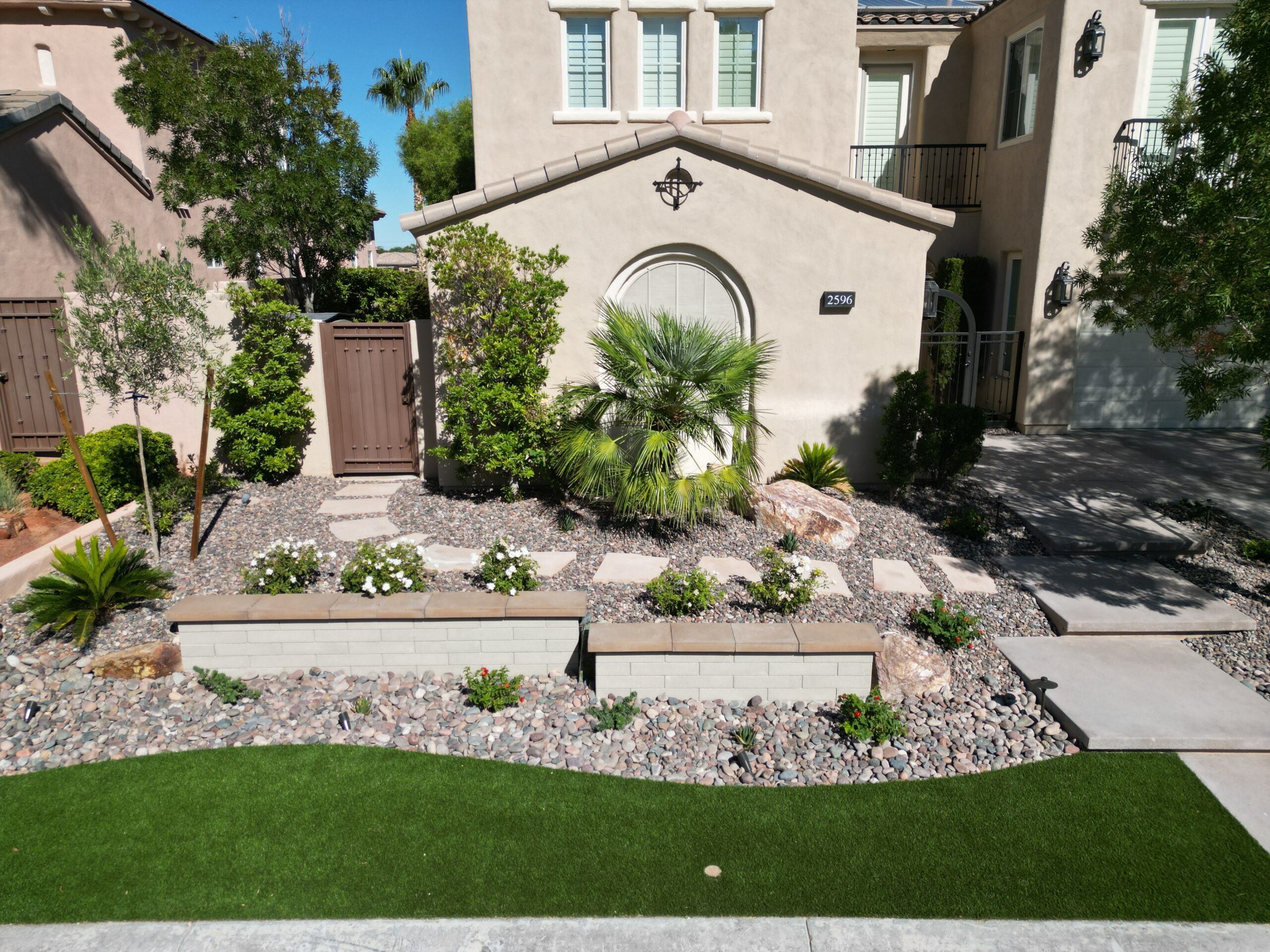 A garden with palm trees and rocks in the yard.